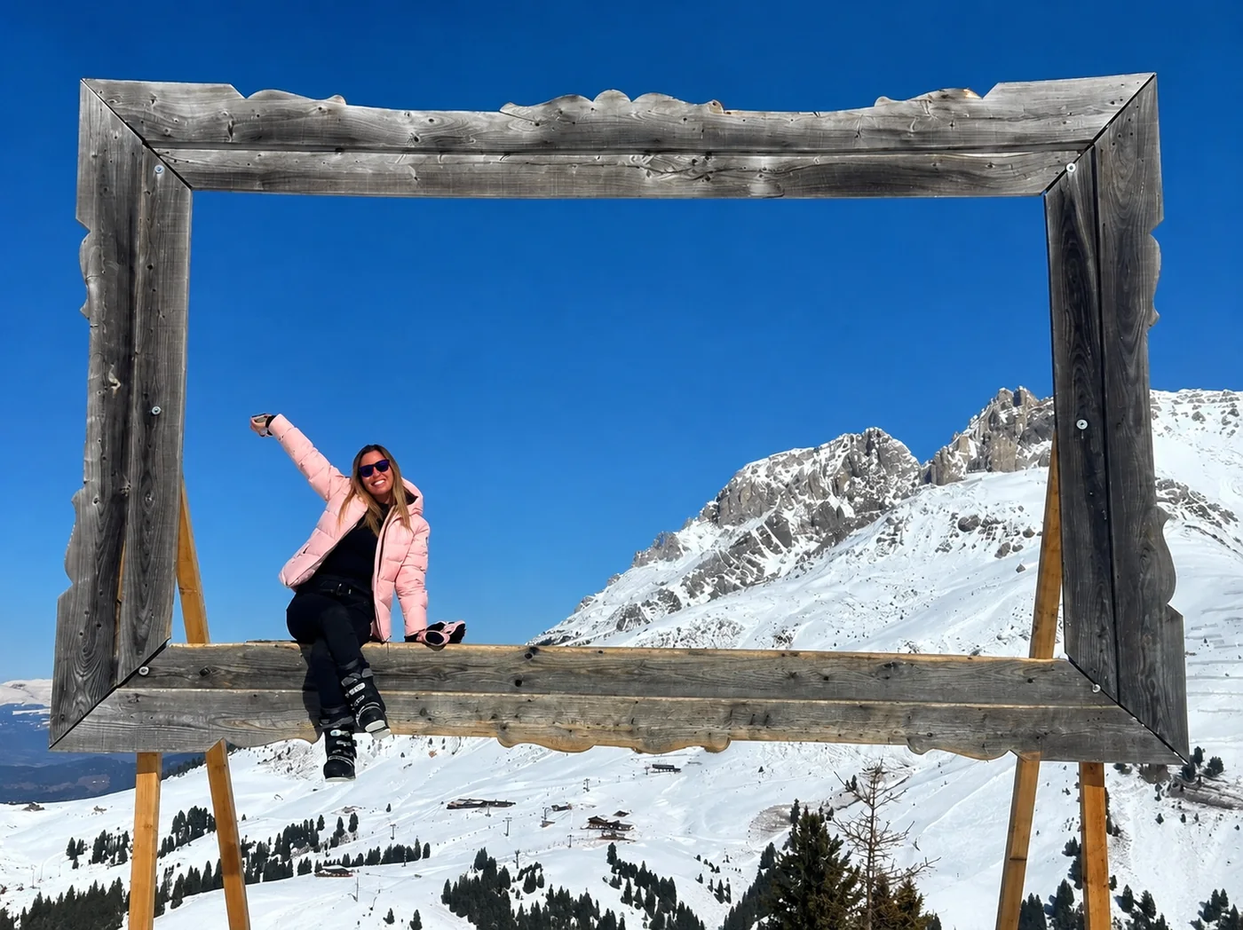 Giulia sitting inside the big wooden frame in the mountains